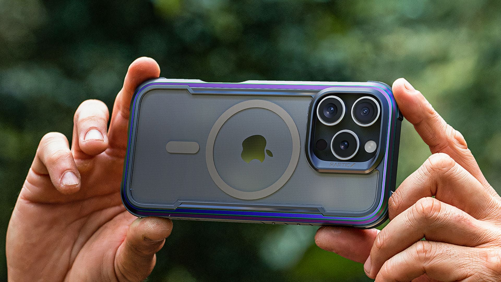 A person holds an iPhone with a protective case, featuring a prominent Apple logo and a circular magnetic design, next to a laptop.