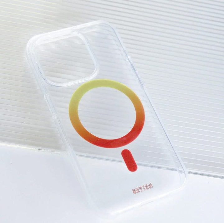 Placed on a white textured surface is the Bryten by Raptic iPhone 15 MagFx MagSafe Case, a clear smartphone case showcasing a red and green circular design. The case offers drop protection and features the word "Bryten" printed in red at the bottom.