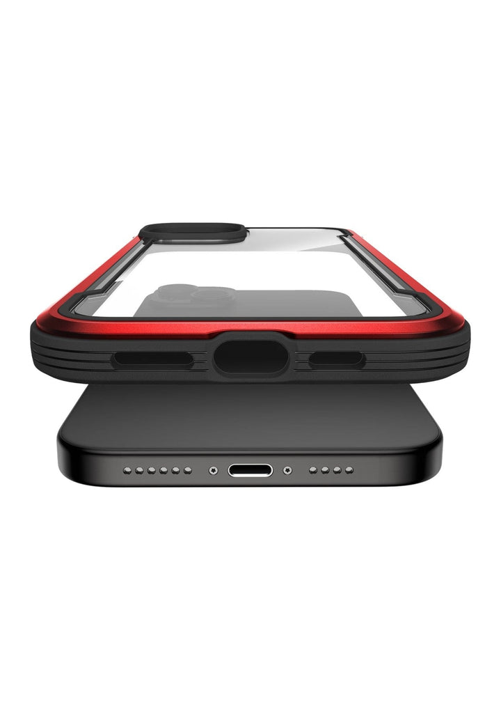 A black smartphone in a red and black Raptic Shield iPhone 15 Shield Case, boasting MIL-STD-810G Standards and 3-metre drop protection, placed on top of a wireless charging pad.