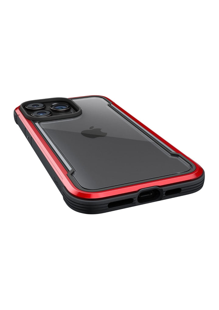 A smartphone with a black and red Raptic Shield iPhone 15 Case, viewed from an angle showing the camera lenses and charging port. This rugged case meets MIL-STD-810G Standards, offering exceptional 3-metre drop protection.