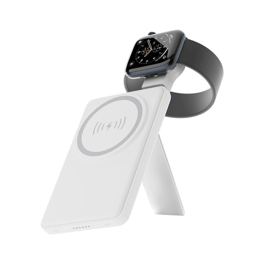 An Urban 6-in-1 MagSafe M6 Wireless Charger Station holds a smartwatch at an angle on its white, foldable structure. The charger features a circular charging area marked with a power symbol. The smartwatch, sporting a black band and analog clock display, is positioned against a plain white background.