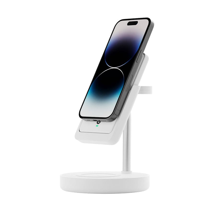 The Urban 6-in-1 MagSafe M6 Wireless Charger Station by Urban is a sleek, white charging stand that holds a smartphone in an upright position. The phone screen displays a minimalistic, dark gradient wallpaper with two overlapping circles. Compatible with iPhone magnetic cases, the station also features an LED indicator light and a circular base for added stability.