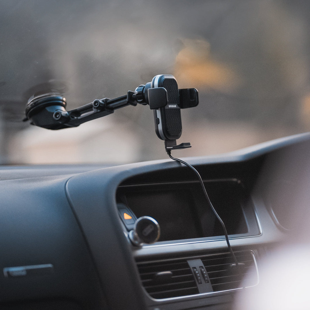 The Urban Wireless Cooling Car Charger - Auto15 Pro (Complete Kit) from Urban is attached to the windshield, securely holding a smartphone in landscape orientation. The phone is connected to the high-speed car charger, ensuring it stays powered throughout your journey.