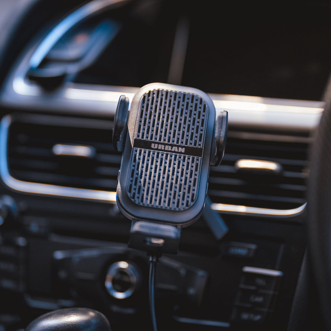 Close-up of a car's dashboard with an Urban Wireless Cooling Car Charger - Auto15 Pro (Complete Kit) attached to an air vent, featuring fast wireless charging capability.