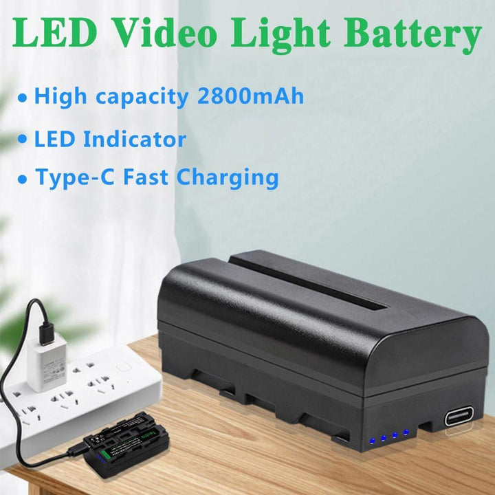 A pair of MobileTechnica Tectra 2800mAh Batteries for Sony NP-F550/F570/F970 sits on a wooden surface, with USB charger and dock plugged into a power strip. Features include rechargeable capacity, LED indicator, and USB-C charging.
