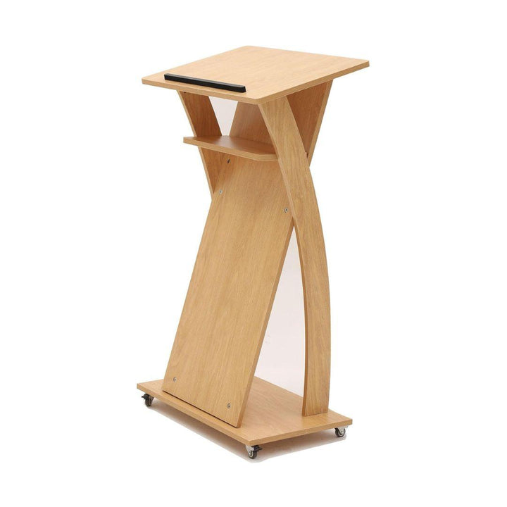 The MobileTechnica Podium Lecturn Rolling Stand features a modern, angular light wood design with a slanted reading surface, black ledge, storage shelves, and curved side panels—all on wheels for easy mobility.