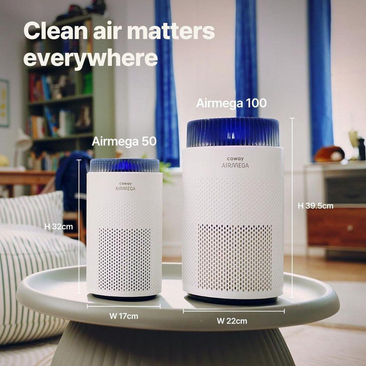 Two white Portable Air Purifier - Coway Airmega 50 units by MobileTechnica sit on a round table in a cozy living room, removing ultrafine particles for fresh, clean air. Text reads: “Clean air matters everywhere.”.