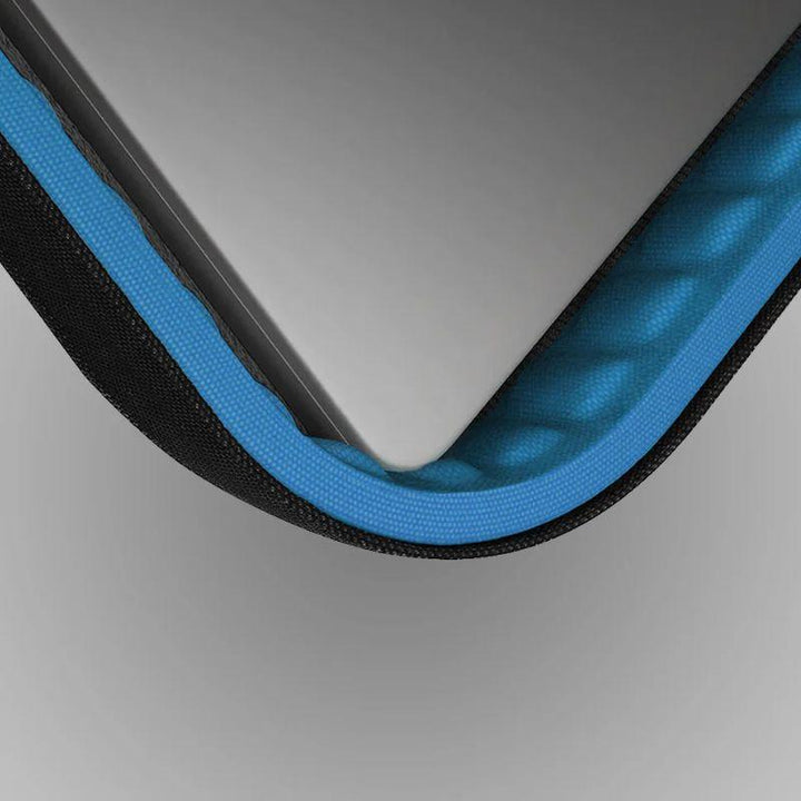 Close-up of a silver laptop in the UNIQ Vienna Laptop Carry Sleeve Shockproof for MacBook Pro 16-inch, featuring a textured blue interior with black trim. The cushioned lining by UNIQ provides durable protection against impacts.