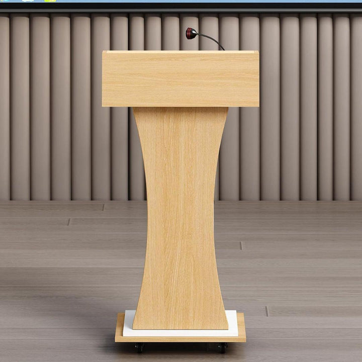 The MobileTechnica Podium Lecturn Rolling Stand, featuring a curved base, storage shelves, and a gooseneck microphone, stands on a light wood floor against vertical taupe wall panels. No people are present.