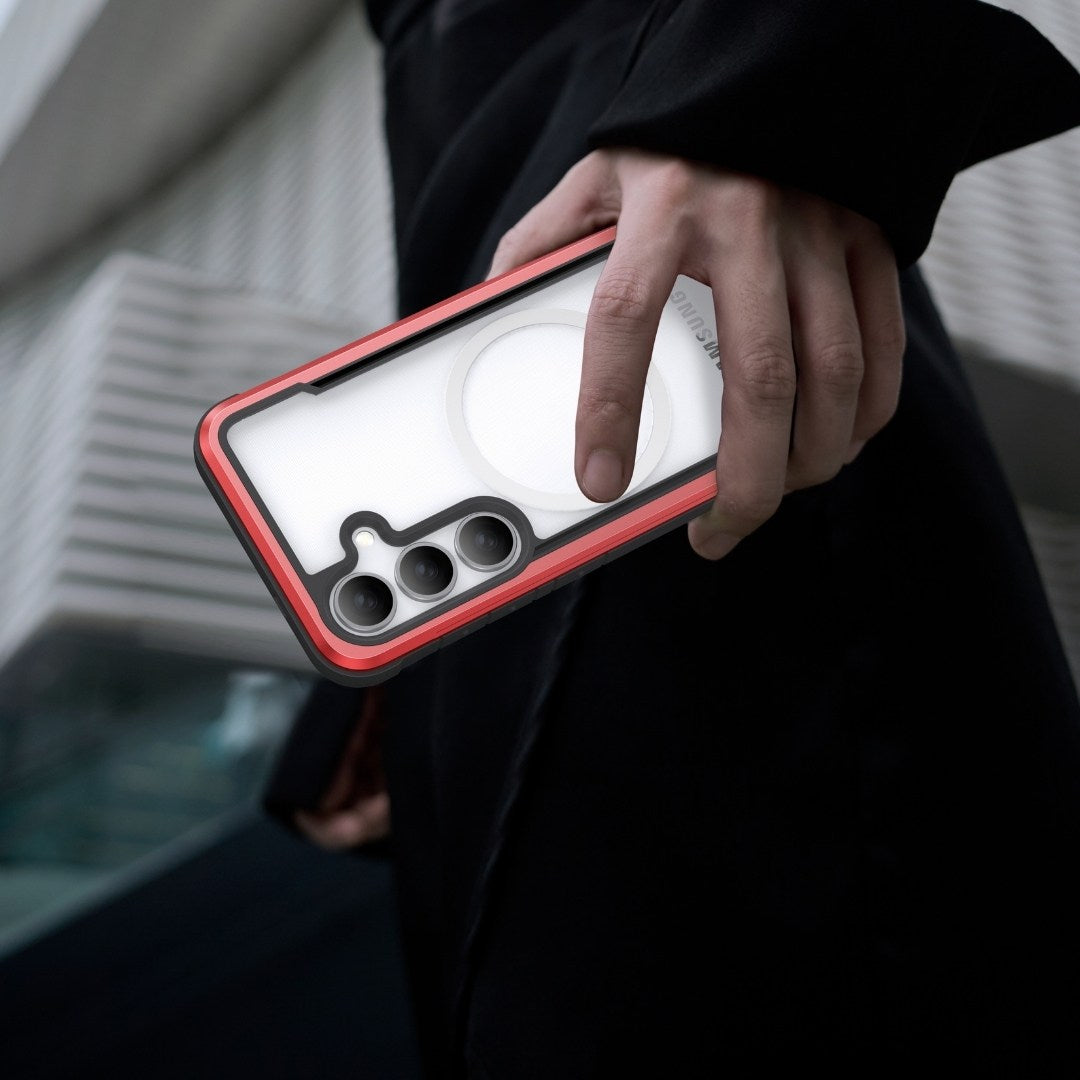 A person in a dark coat holds a Samsung Galaxy S25 with a transparent back showing distinctive circular and elliptical designs and three camera lenses. The Raptic Shield case, providing military-grade protection with red edges, is set against a backdrop of modern geometric architecture.