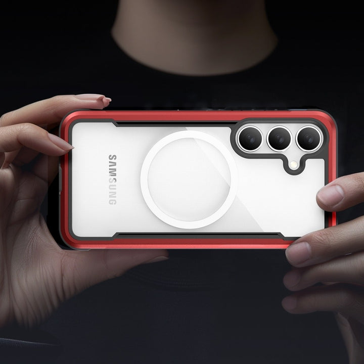 Two hands hold a Samsung smartphone with a triple camera, encased in the sleek Samsung S25 Shield Case by Raptic. The case offers military-grade protection with its black and red exterior, while the device's holder is partially obscured against the dark backdrop, adding mystery.