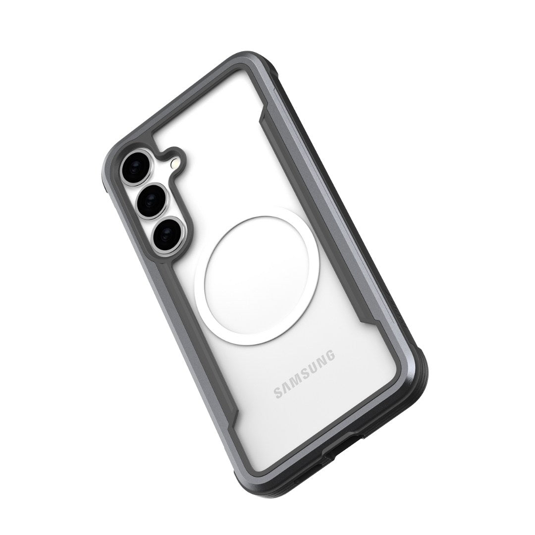 The Samsung Galaxy S25 in a Raptic Shield case offers military-grade protection. The gray and black case has a clear back revealing the Samsung logo and three cameras. A circular white holder adorns the back, with the phone slightly angled left.