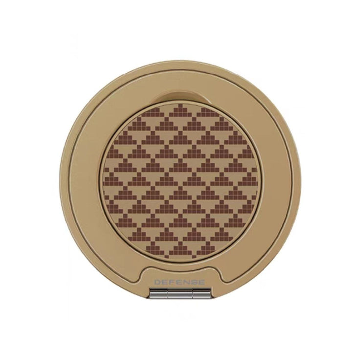 The Raptic Defeme Magnetic Ring with Pop holder by MobileTechnica features a round, beige compact case and pixelated brown pattern on the lid. “DEFENSE” is printed near the latch among geometric rectangles, closing via a hinged bottom.