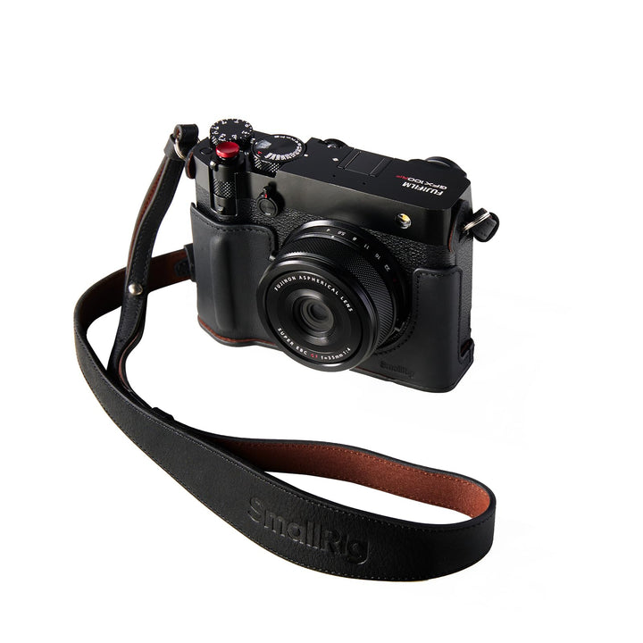 A FUJIFILM GFX100RF camera is shown with the SmallRig GFX100RF Leather Case Kit, featuring a brown leather case, black thumb pad, concave shutter button cap, and wide shoulder strap for comfort and stylish protection against a white background.