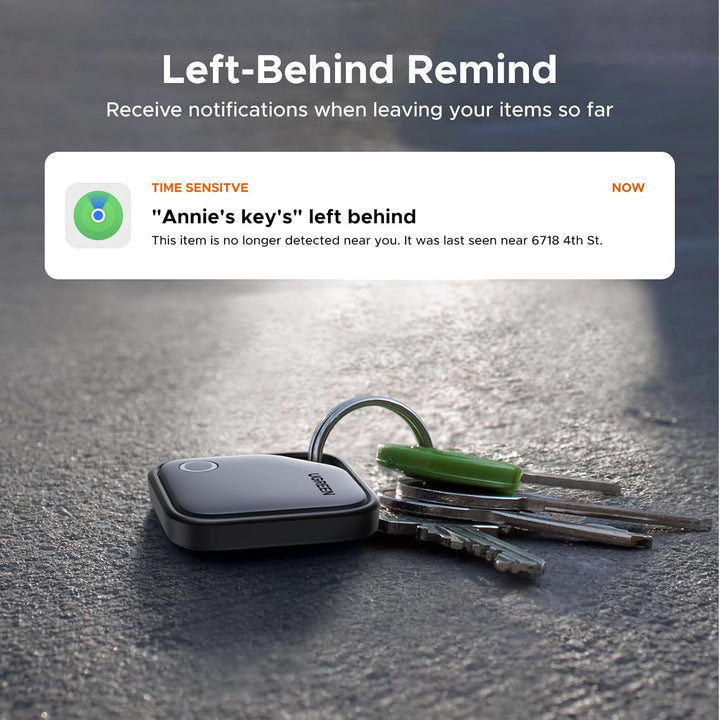 A set of keys with a UGREEN 2 Pack FineTrack Smart Finder Bluetooth Tracker Tag lies on a gray surface. A notification says: "'Annie's key's' left behind. This item is no longer detected near you." The background is softly blurred.