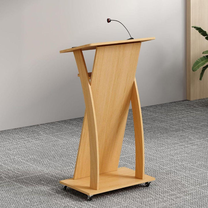 The MobileTechnica Podium Lecturn Rolling Stand for Lectures features a modern ergonomic design with a slanted reading surface, storage shelves, and attached microphone, set on a gray carpeted floor near a white wall and green plant.