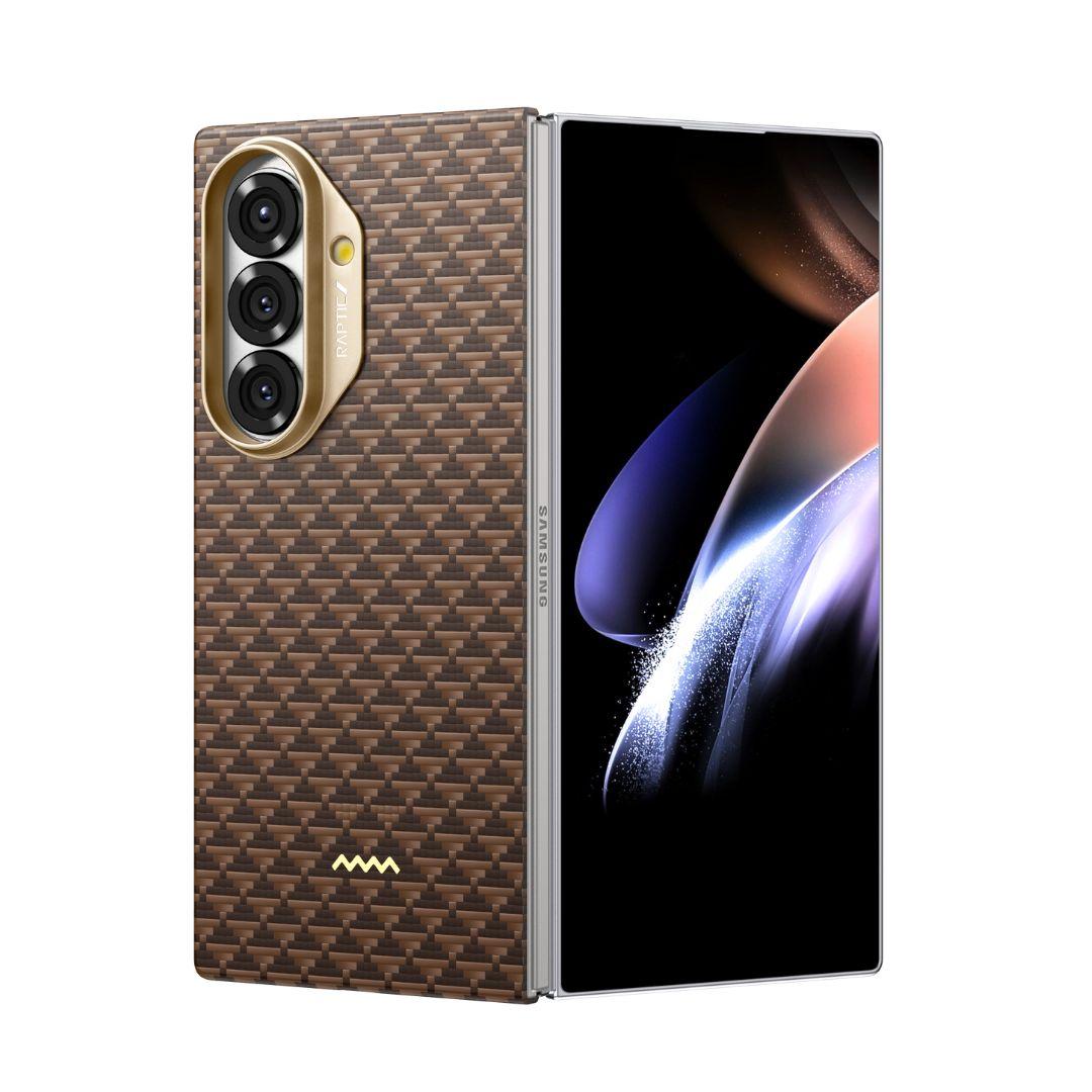 A foldable smartphone is shown partially open with a brown, carbon-fiber textured RAPTIC Humble Desert skin case for Samsung Galaxy Fold 7, featuring three rear cameras in a gold vertical oval housing. "Samsung" appears on the protective hinge.