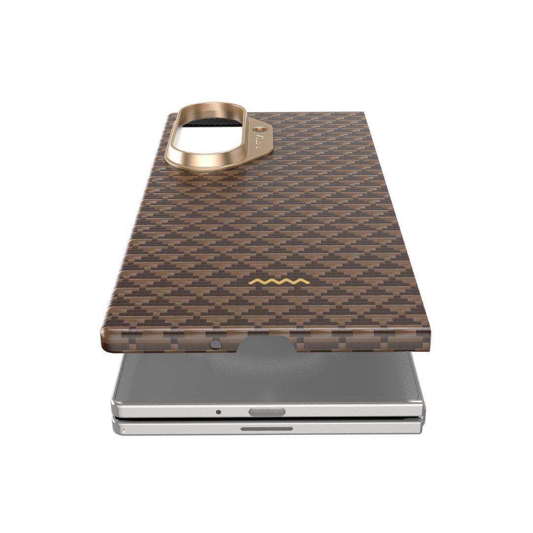 The RAPTIC Samsung Galaxy Fold 7 Skin Case - Humble Desert features a brown and gold checkered design, raised gold camera cover, hinge protection, camera cutout, and a small gold zigzag logo, displayed above a silver phone on a plain white background.