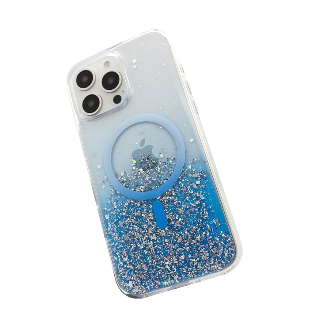 A silver iPhone with three camera lenses is encased in the Bryten Starburst MagSafe for iPhone 16 Pro Max. The Bryten case contains blue and silver glitter along the bottom and features a blue MagSafe ring in the center for seamless wireless charging. The Apple logo is visible through the clear section of the case.