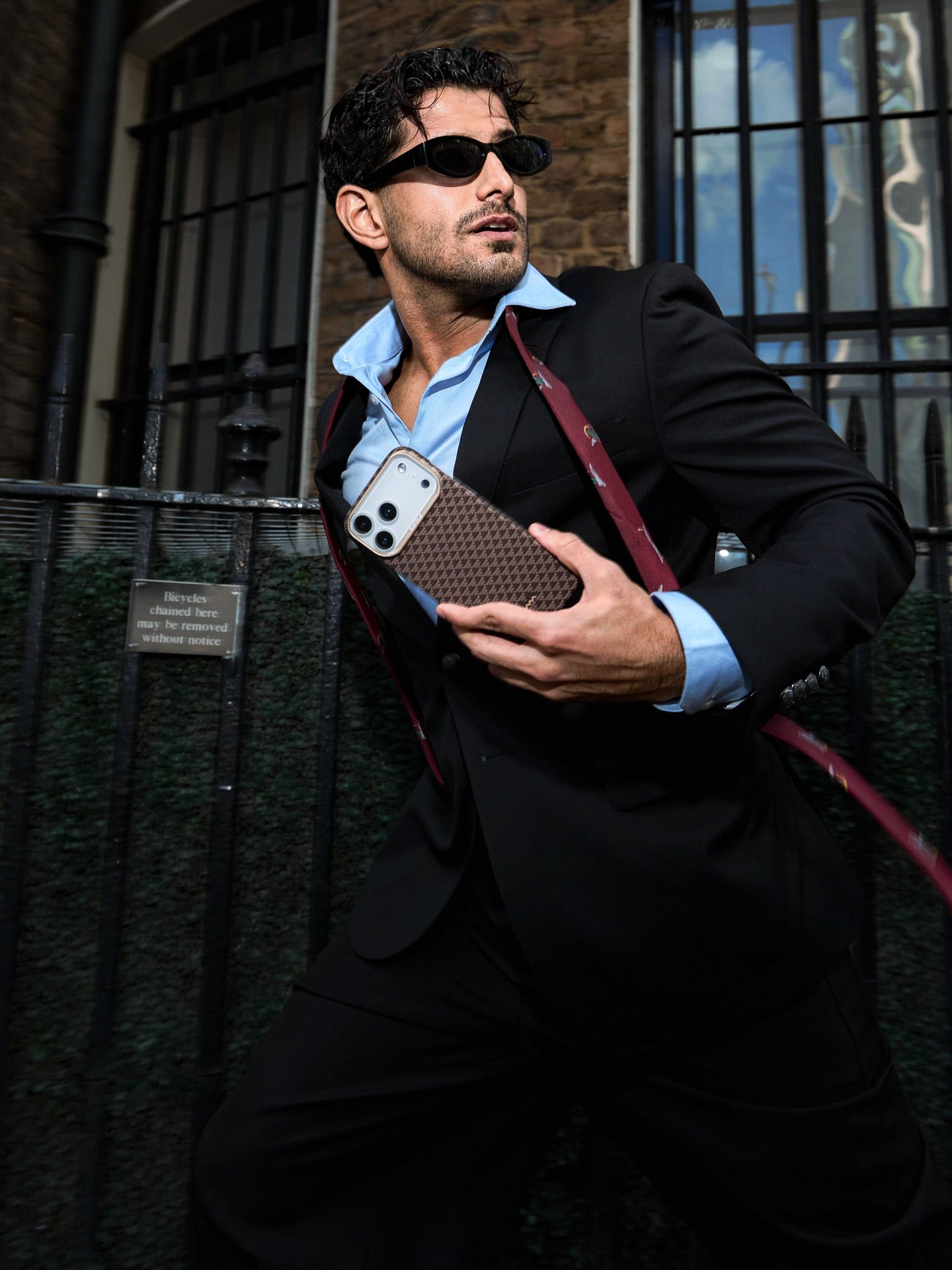 Man holding a phone case against a brick wall background