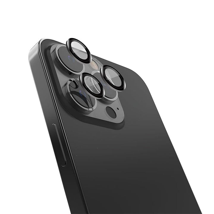 Close-up image of the back of a sleek, black Raptic Armour iPhone 16, 16 Plus highlighting its camera module, which features three lenses protected by a Raptic anti-fingerprint camera shield and a flash. The device's sharp edges and polished surface are prominent, with the volume button visible on the left side. The background is plain white.