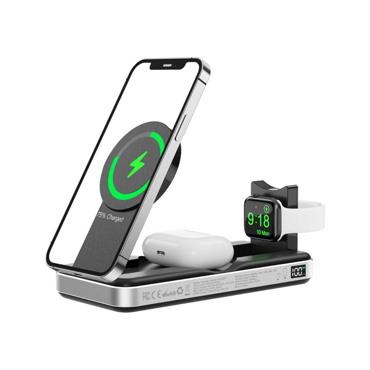 An elegant, travel-friendly Urban PowerBuddy 5in1 Wireless MagSafe Powerbank 2 in use, charging a smartphone, wireless earbuds, and a smartwatch simultaneously. The smartphone's screen displays a green circular charging icon with "75% Charged," and the smartwatch screen shows the time "9:18 Mon.