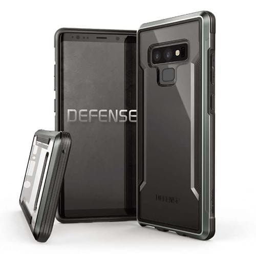 Two rugged smartphone cases, one in black and the other in gray, with the word "DEFENSE" displayed, are shown protecting a smartphone. One of the X-Doria Defense Shield Samsung Galaxy Note 9 Cases by Raptic is displayed upright while the other is angled. Both military-grade protective cases are wireless charging compatible.