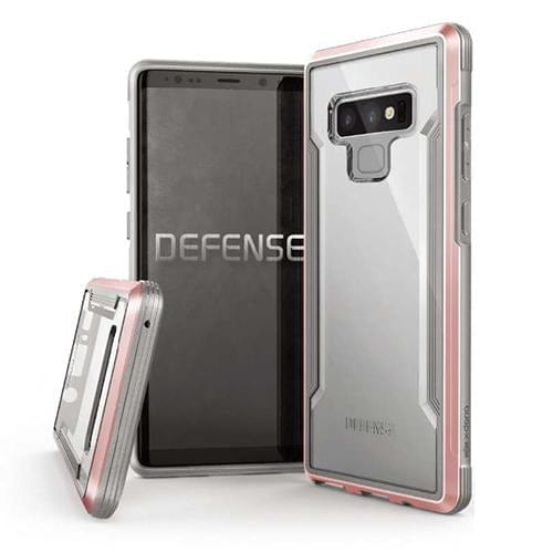 Two smartphones are displayed with clear, rugged cases. One phone is standing vertically, screen on, showing the "Raptic" logo. The other phone is laying down, revealing the back of the military-grade X-Doria Defense Shield Samsung Galaxy Note 9 Case that is also wireless charging compatible.