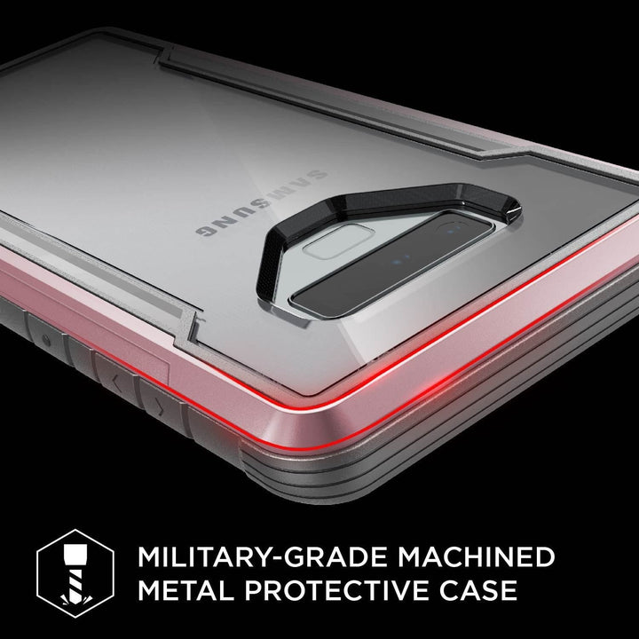 Close-up of a Samsung Galaxy Note 9 enclosed in an X-Doria Defense Shield case by Raptic. The military-grade machined metal case showcases a robust design with reinforced edges, a clear camera cutout, and compatibility with wireless charging.